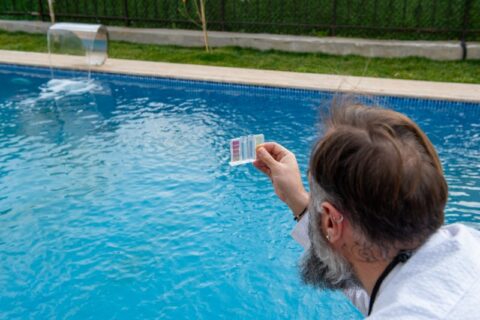 Person testing swimming pool water quality using test kit in Virginia & Maryland