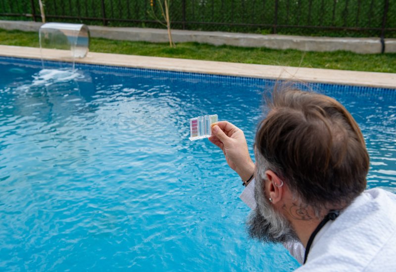 Person testing swimming pool water quality using test kit in Virginia & Maryland