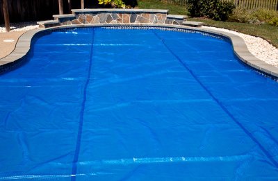 Blue Swimming Pool Cover Spread Over a Large Pool for Maintenance