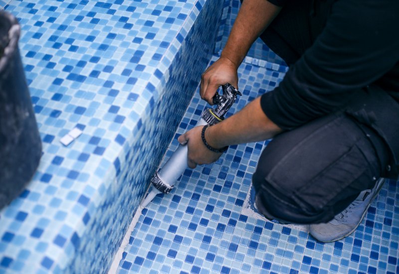 Worker Sealing Blue Mosaic Tiles in a Swimming Pool in Virginia & Maryland