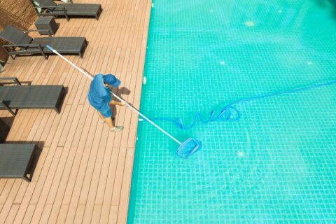 Pool Professional Cleaning a Residential Pool Using a Long-Handled Net in Virginia & Maryland