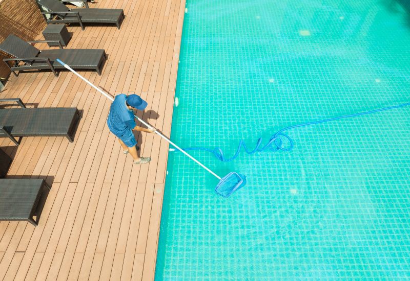 Pool Professional Cleaning a Residential Pool Using a Long-Handled Net in Virginia & Maryland