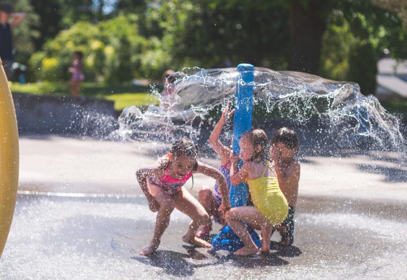Children playing around a splash pad water feature on a sunny day in Virginia & Maryland