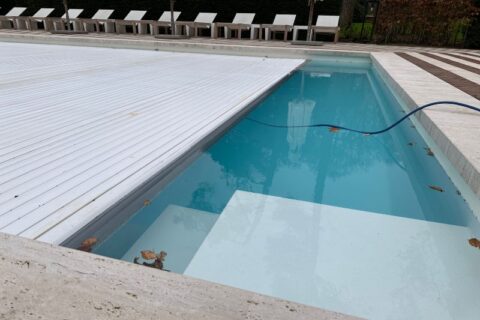 Swimming pool with retractable cover partially closed and hose in water in Virginia & Maryland